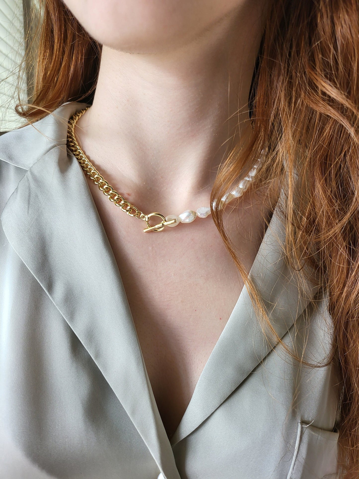 May include: A gold chain necklace with a toggle clasp and a pearl strand attached to the clasp.